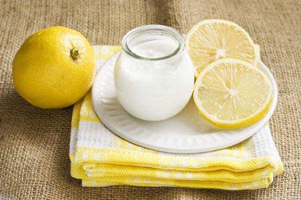 vaso de cristal con yogur y un limón y varias rodajas de la fruta alrededor