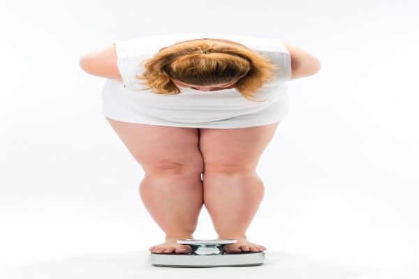 Obesidad - mujer obesa sobre una bascula controlando su peso