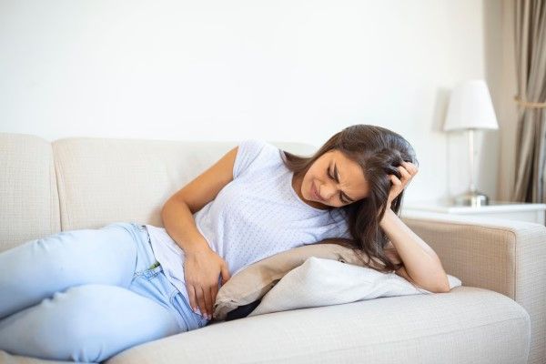 amenorrea - mujer tumbada en el sofá con dolores en los ovarios