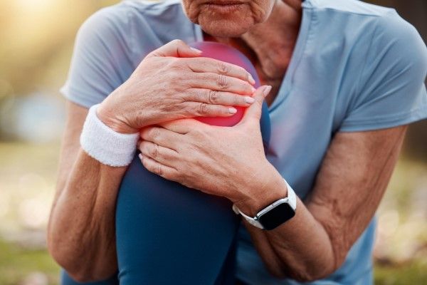 Osteomelitis - mujer mayor agarrándose con gesto de dolor la rodilla