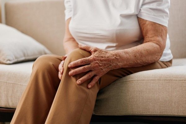 Osteomielitis - mujer mayor agarrándose con gesto de dolor la rodilla