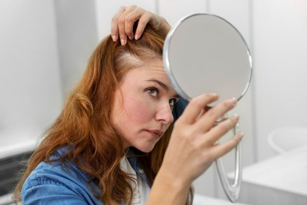 Trasplante capilar femenino - mujer mirando en el espejo sus problemas de alopecia