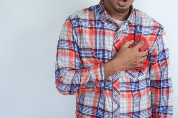 Cardiopatía Isquémica - Hombre joven con dolor de corazón sosteniendo la mano en el pecho con riesgo de ataque cardíaco