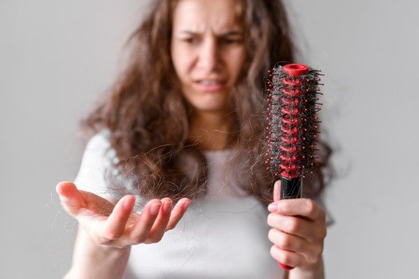 mujer joven preocupada por el mechón que tiene en la mano y el cabello del cepillo