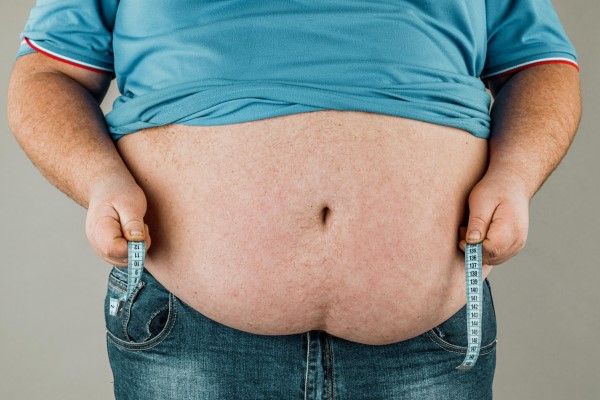 obesidad - hombre obeso con una cinta para medir el contorno de su cintura