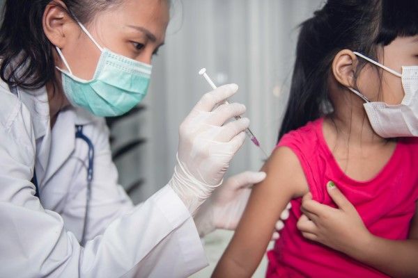 medico aplicando una vacuna a una niña en el brazo