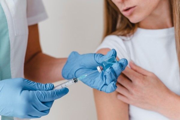 medico preparando una vacuna para aplicarla a una mujer