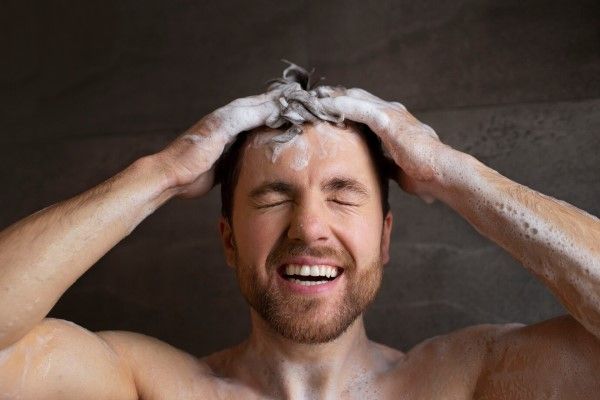 hombre enjabonándose el cabello
