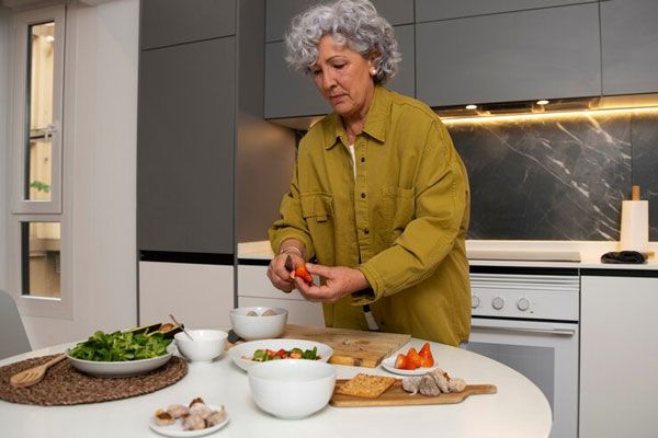 Enfermedad de Alzheimer - Mujer canosa de cabello rizado intenta mantener la concentración para preparar una comida en casa