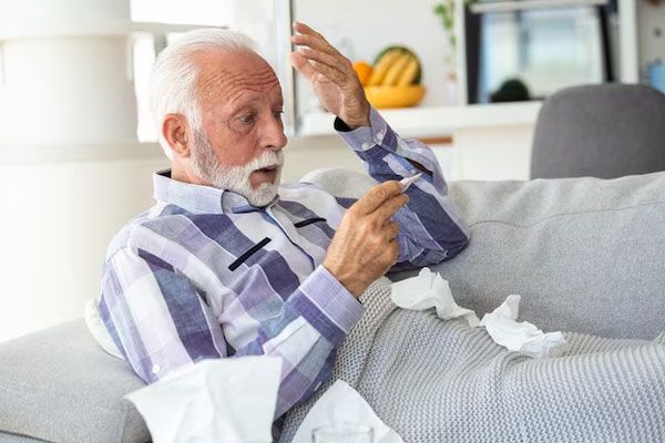 Gripe - Adulto mayor resfriado se muestra visiblemente sorprendido con su temperatura corporal