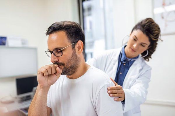 Gripe - Doctora examina los pulmones de un paciente con tos persistente