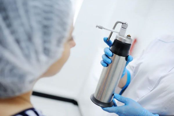 Verrugas comunes - Doctor aplica terapia de enfriamiento para secar y remover lunares protuberantes en el rostro de una paciente 
