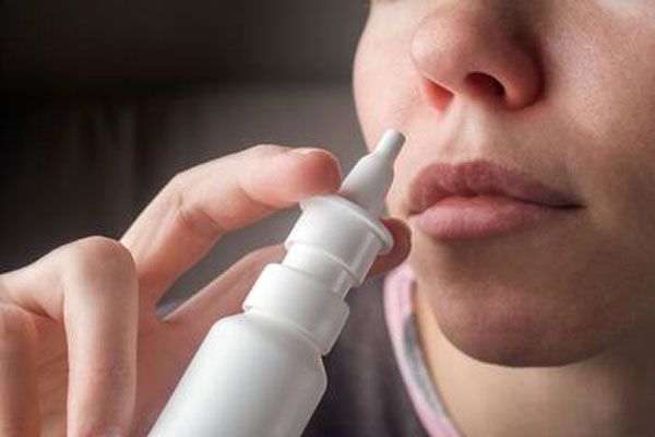 Mujer usa un atomizador nasal para administrarse un medicamento sintético que le ayude con su proceso de coagulación 