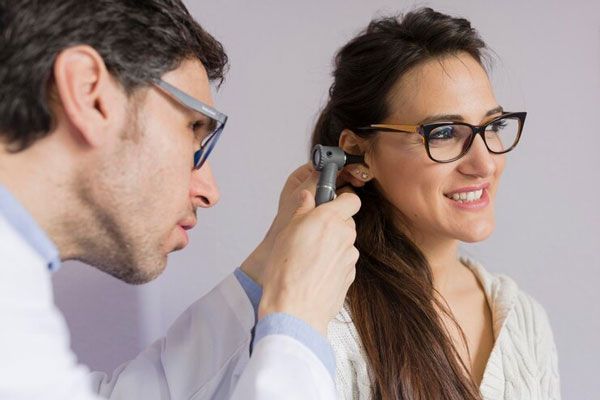 Pérdida de la audición - Doctor realiza una revisión exhaustiva del canal auditivo de una paciente con lentes 