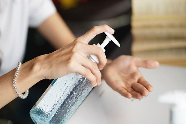 Mujer tomar un frasco de gel antibacterial para desinfectar sus manos de manera eficaz 