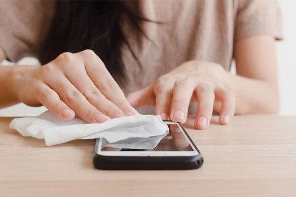 Gripe - Joven toma una toalla desechable para limpiar eficazmente la pantalla de su teléfono