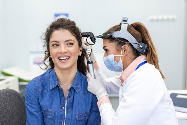 Doctora usa un otoscopio para verificar la salud auditiva de una paciente