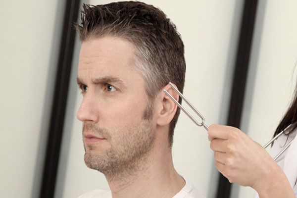 Pérdida de la audición - Especialista en audiología utiliza un diapasón para activar estímulo sensoriales en un paciente 