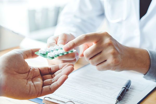 Doctor prescribe una serie de medicamentos para aliviar los síntomas de infección en un paciente 