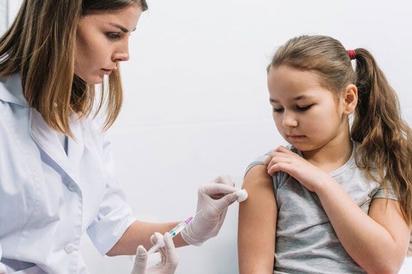 Hepatitis A - Doctor aplica vacuna en el brazo de una niña para prevenir enfermedades 
