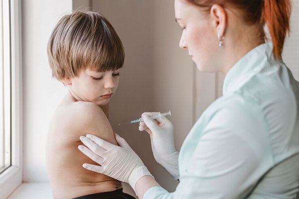 Enfermera toma del brazo a un niño para aplicar una vacuna que aumentará su inmunidad frente al VPH 