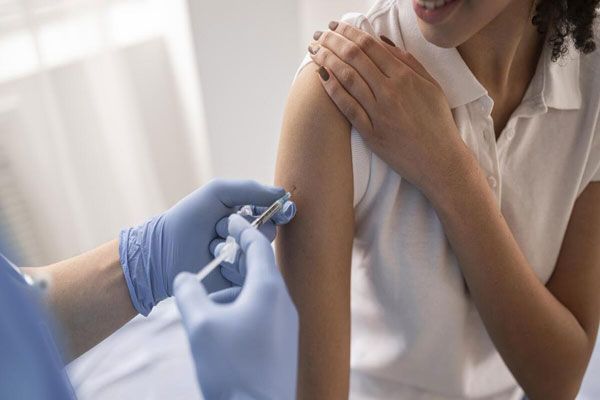 Gripe - Enfermera aplica una vacuna en el brazo para aumentar los niveles de inmunización contra diversas enfermedades