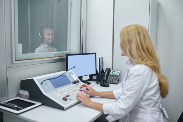 Especialista realiza un examen auditivo para evaluar la capacidad de escucha de un niño 