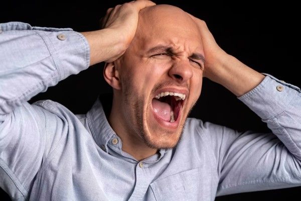 hombre llevándose las manos a la cabeza mientras grita