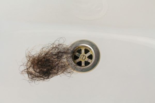 restos de cabello al lado del desagüe de la ducha