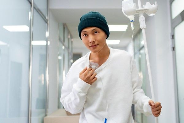 Fiebres de origen desconocido - joven asiático paseando por el hospital mientras recibe un tratamiento medico intravenoso