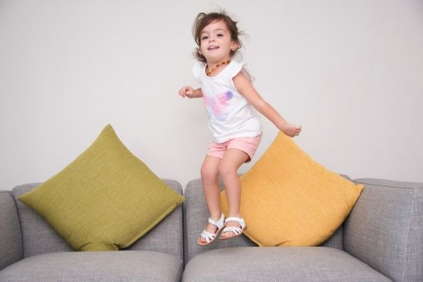 Síndrome de Rett - niña pequeña saltando en el sofá de la casa