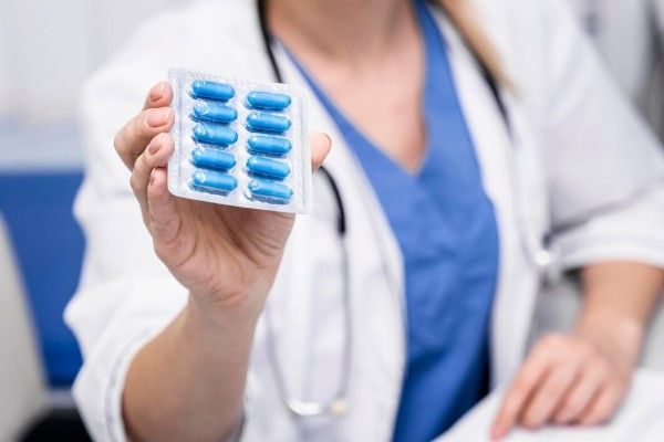 doctora mostrando en su mano un blíster de pastillas azules