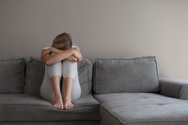 Disfunción sexual femenina - mujer sentada en el sofá en posición fetal