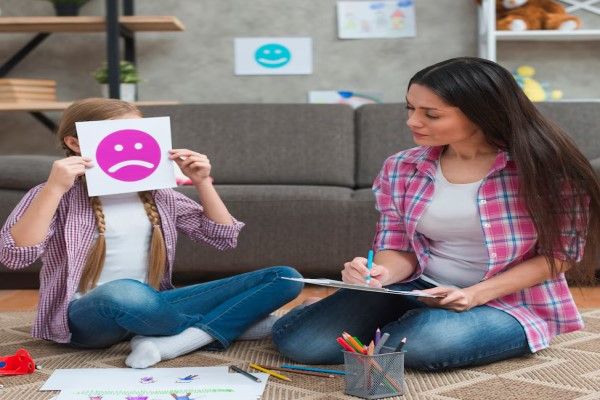 Síndrome de Rett - especialista ayudando a una niña en su consulta usando dibujos
