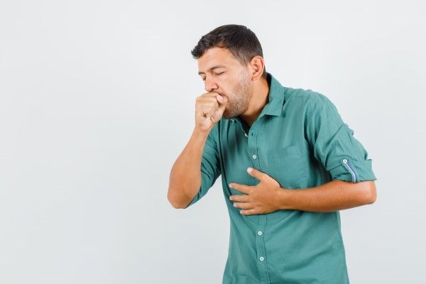 hombre tosiendo con el puño en la boca y la otra mano en el pecho