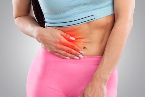 mujer llevándose la mano al costado del vientre con signos de dolor en la zona