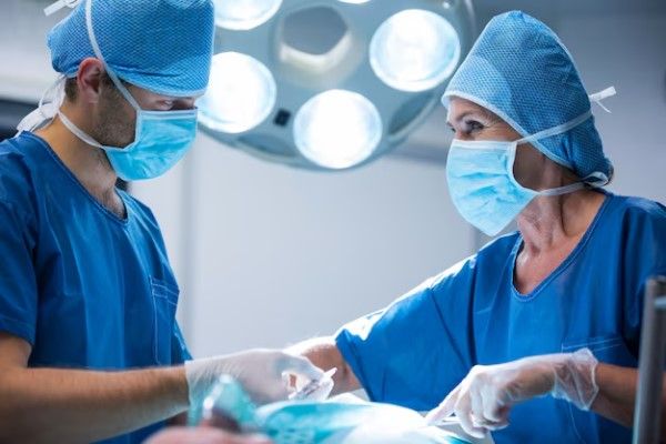  pareja de cirujanos en quirófano operando a un paciente