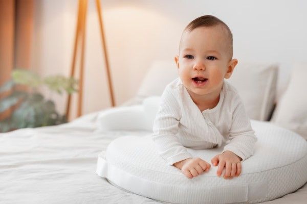 bebe sobre un cojín encima de la cama