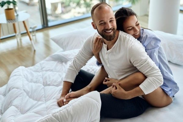 pareja sonriente abrazados en la cama