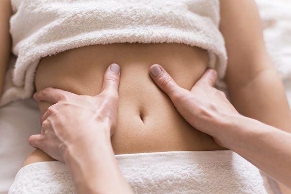 Especialista realizando un masaje en el abdomen de una mujer