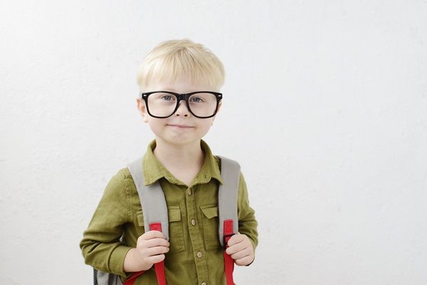 Albinismo - Niño de cabello rubio con lentes llevando una mochila en su espalda
