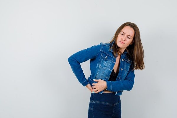 Pielonefritis - Mujer joven tocando con sus manos la zona lumbar con cara de dolor