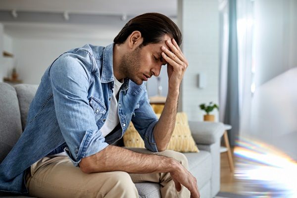 Azoospermia - Hombre sentado tocándose la cabeza con cara de dolor y malestar