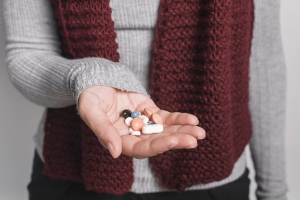 Mujer sosteniendo en su mano varias píldoras de medicamentos