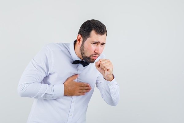 Derrame pleural - Hombre joven poniéndose la mano en el pecho mientras tose, un derrame pleural sintomas
