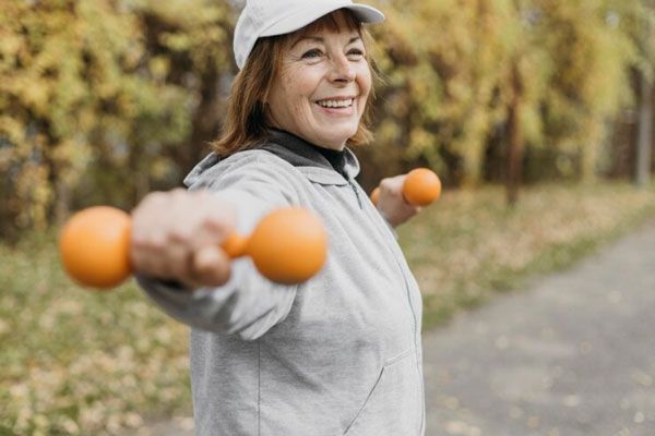Mujer mayor entrena con pesas al aire libre 