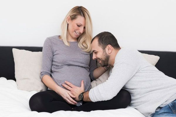Progeria neonatal - Hombre feliz acaricia la barriga una mujer embarazada 