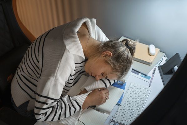 Narcolepsia - Mujer durmiendo sobre cuadernos y libros en un escritorio