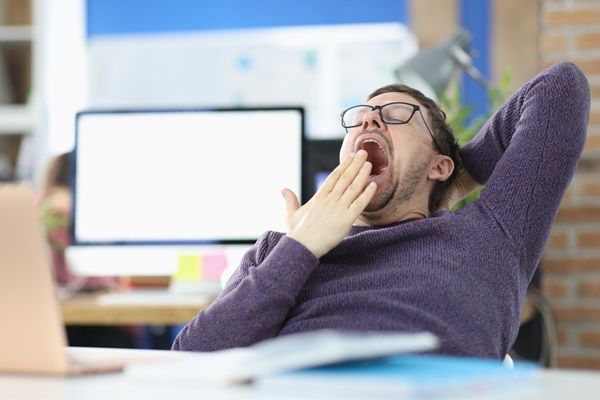 Narcolepsia - Hombre bostezando y con cansancio mientras está en el trabajo