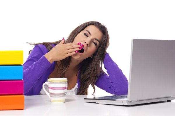 Narcolepsia - Mujer joven con sueño y cansancio bostezando mientras usa la computadora